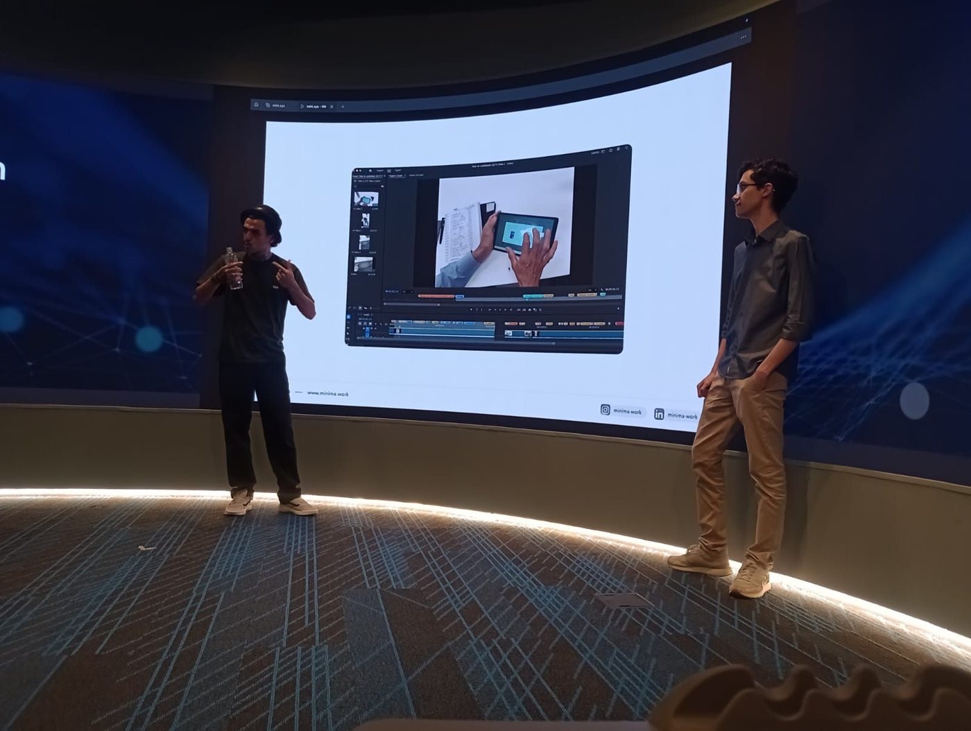 Dois apresentadores ao lado da tela com um teste de usabilidade em vídeo
